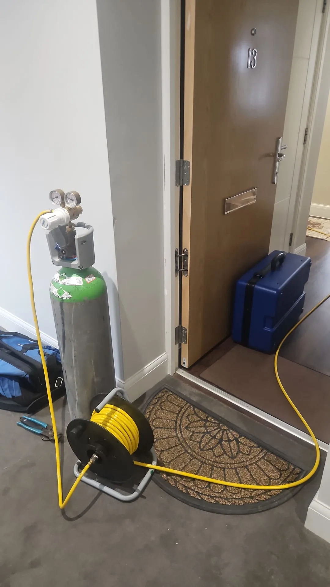 Tracer gas cylinder and yellow test hose positioned at an open flat doorway