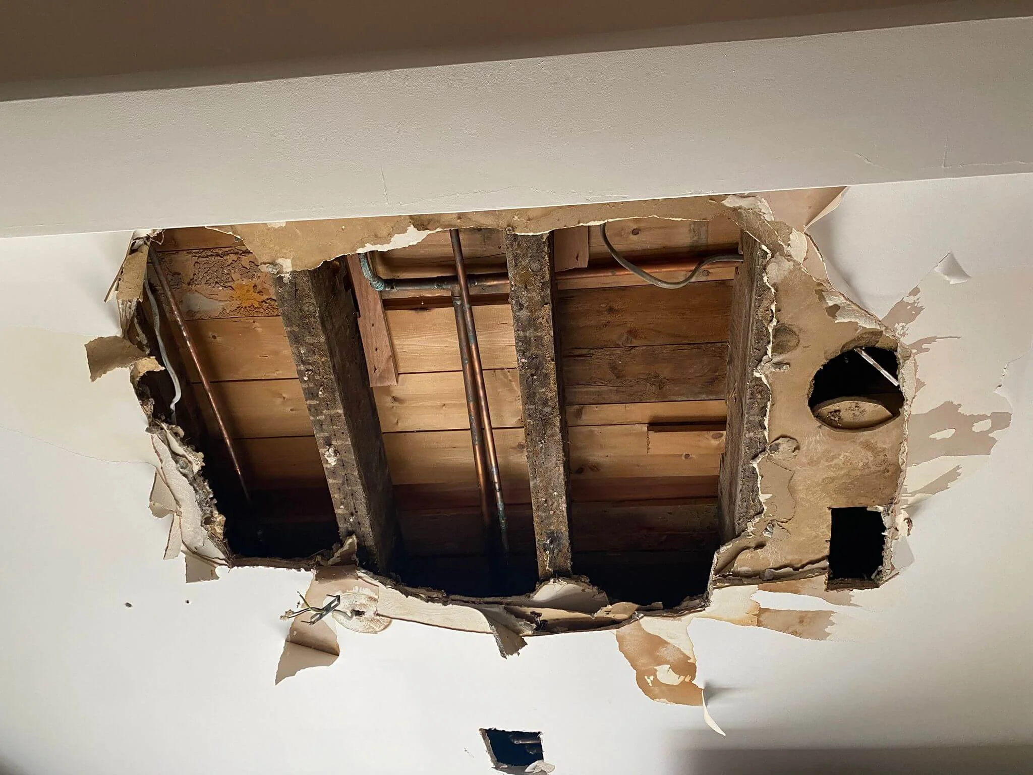 Ceiling opened to expose pipework during water leak detection in Reading