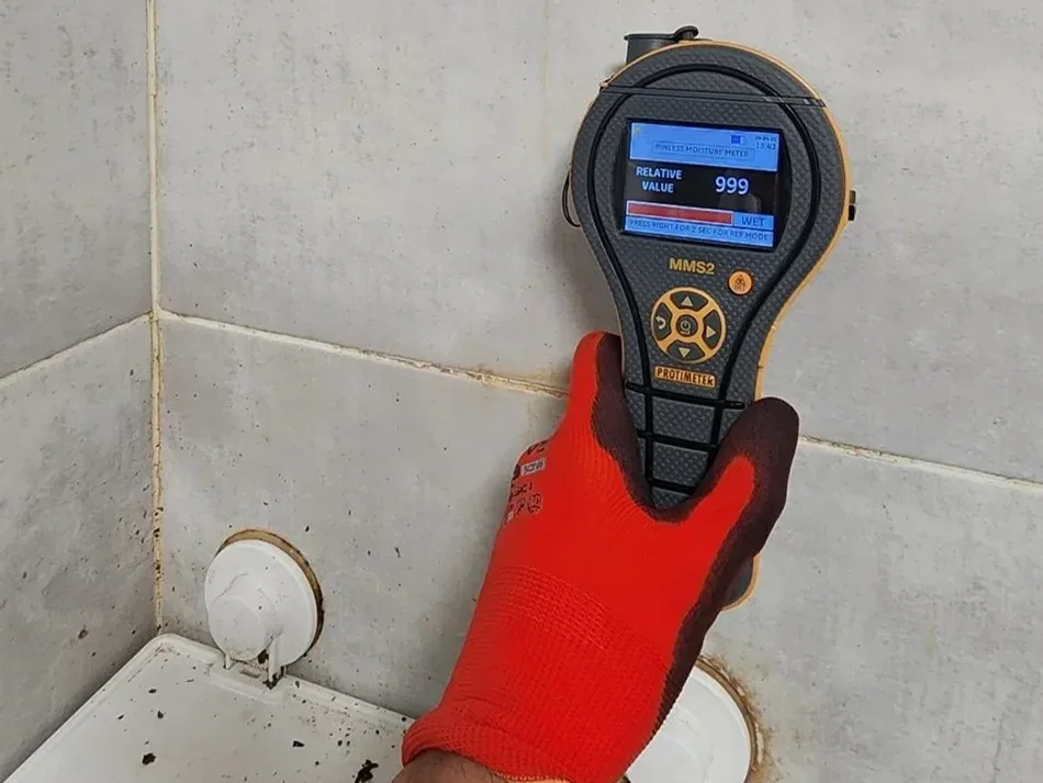 Moisture meter used during bathroom water damage assessment